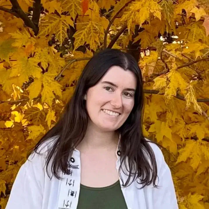 Annie smiling with a backdrop of autumn leaves