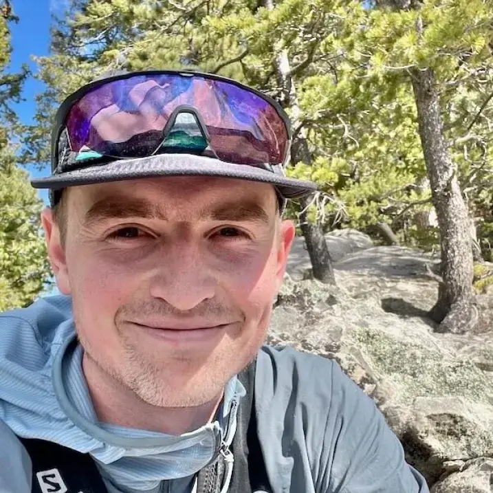 Gordon in running gear in front of a rocky slope with pines