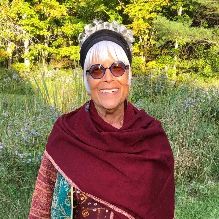 Photo of TwoTrees wearing dark red shawl with summer golden hour sunlight gracing a forest edge