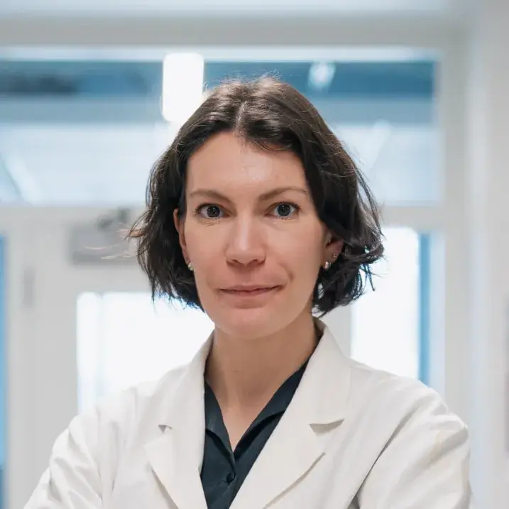 A person with brown hair wearing a white laboratory coat