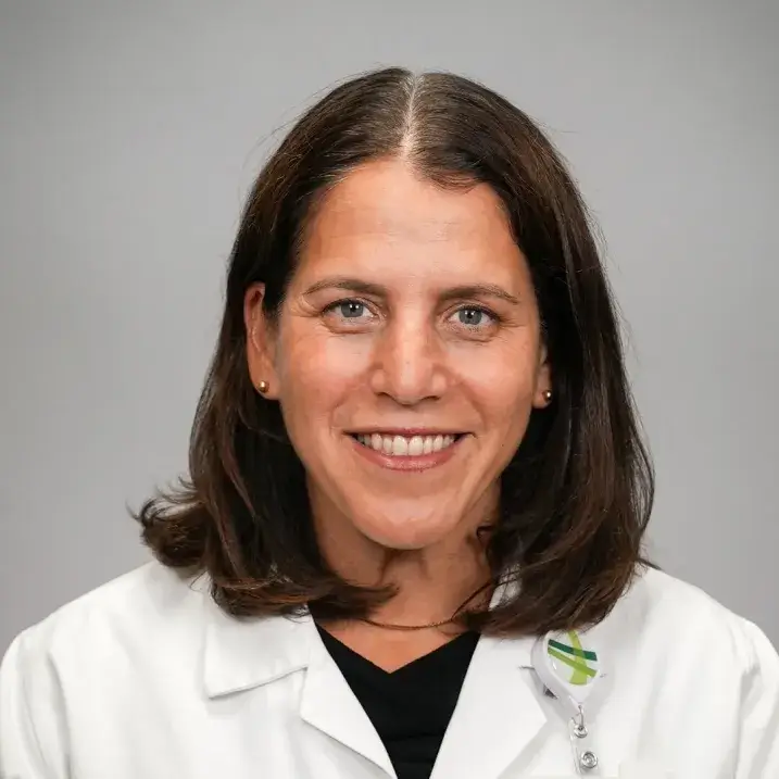 woman with shoulder length dark hair wearing a doctors coat 