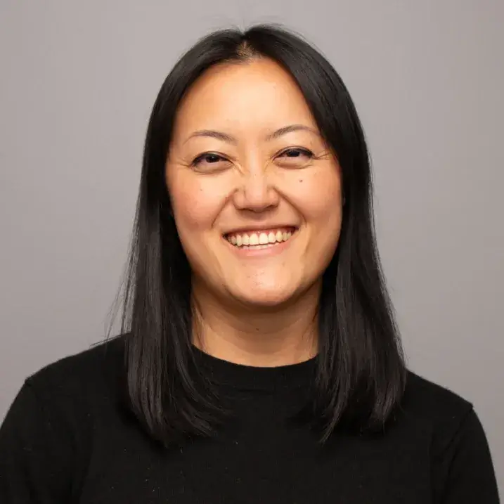 Smiling woman with straight shoulder length black hair, wearing a black sweater