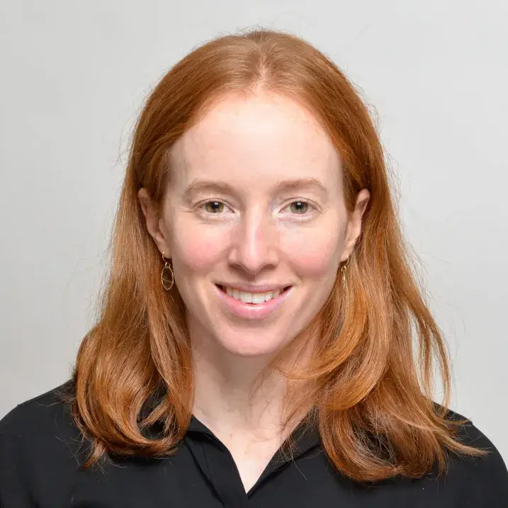 woman with long auburn hair wearing a black collared shirt