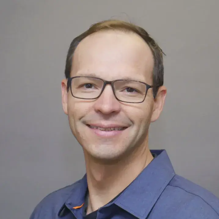 light skinned man with glasses, short brown hair wearing a blue dress shirt