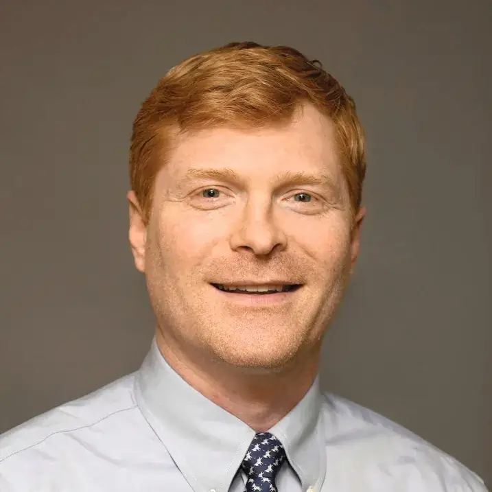 light skinned man with short red hair wearing a dress shirt and tie