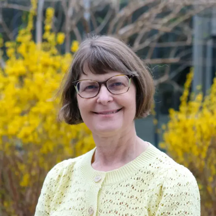 light skinned woman with bobbed brown hair and a pale yellow sweater top