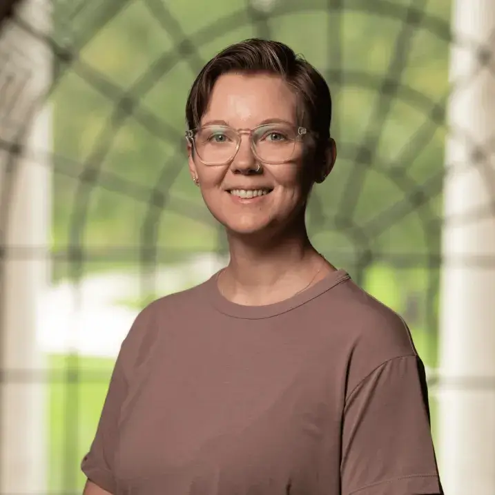 A photo of Meg C Jones standing before a large window.