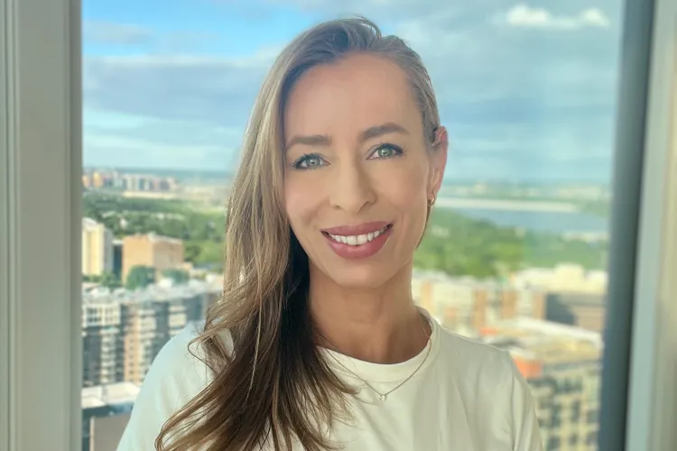 woman with long blond hair standing in front of window overlooking city