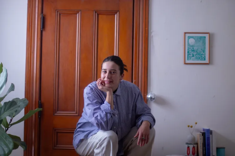 young woman crouched down with hand under chin in front of interior door