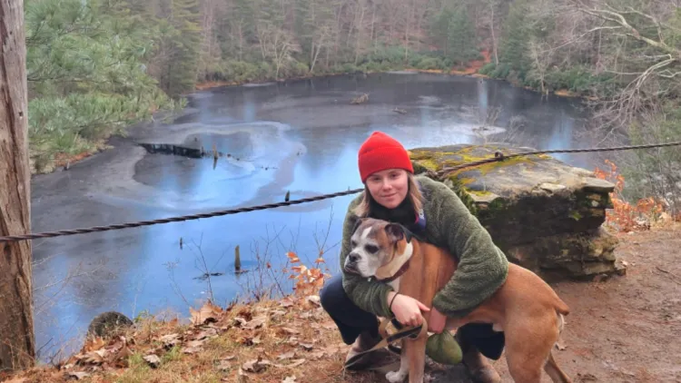 Katie Wynn '22 in crouching in front of pond with dog