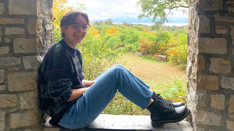 August sitting in a stone nook with greens and yellows in the background
