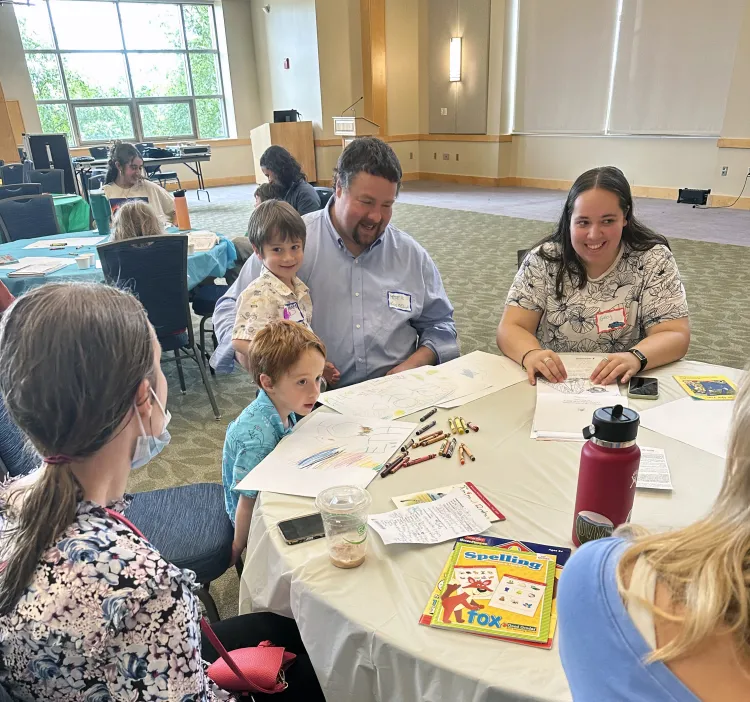 A family of four sit at a round table.
