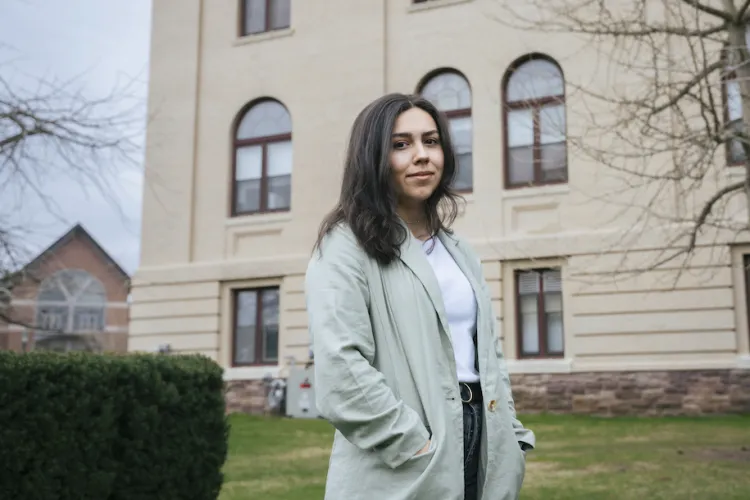student standing in front of brick building on UVM campus