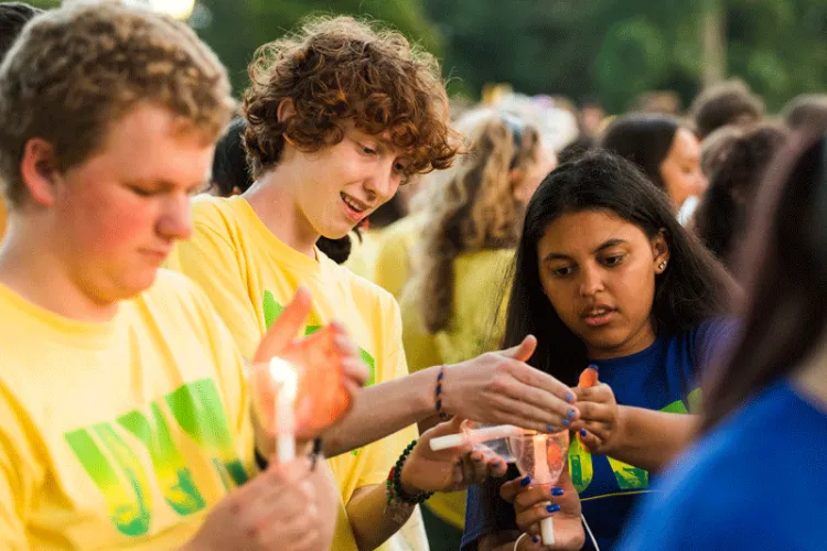 Two students work together to light their candles.