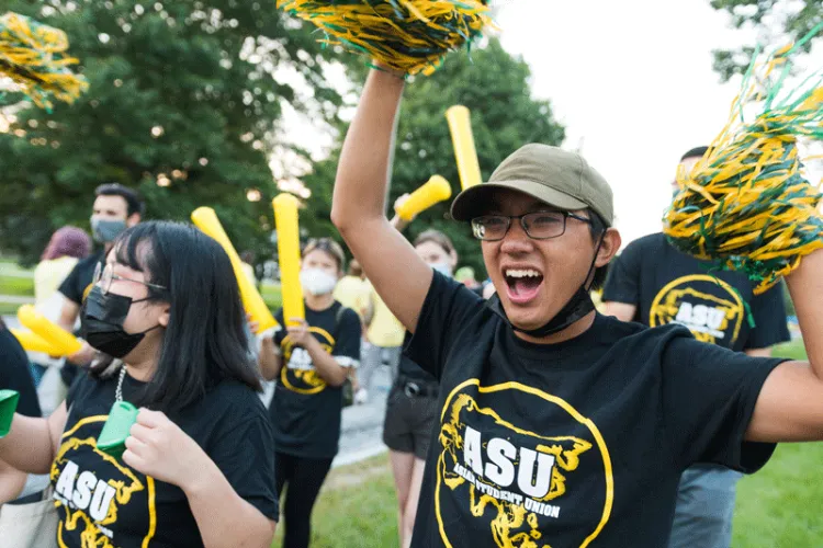 Student in Asian Student Union waves cheer poms with school pride.
