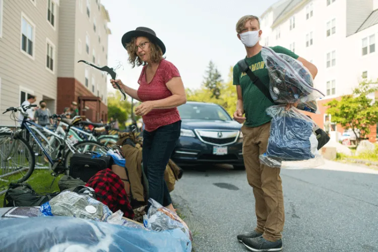 Woman and student pile belongings in front of residence hall