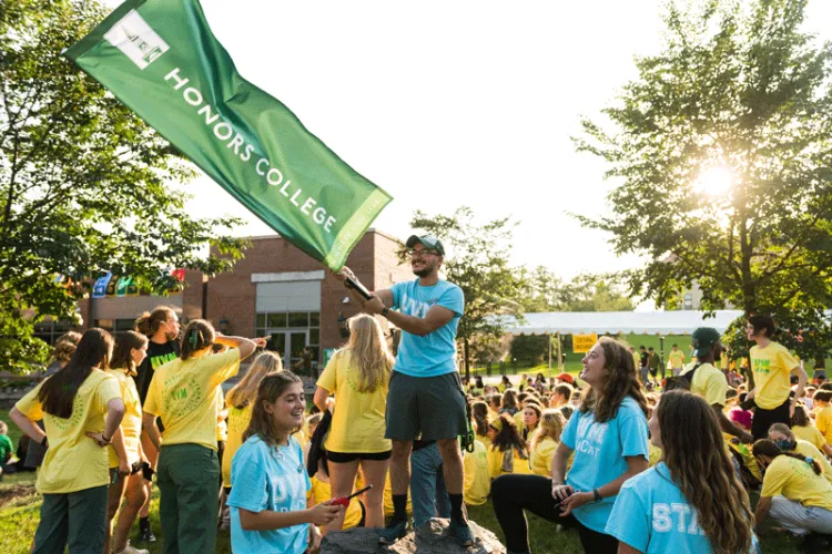 Student leader waves flag for the Honors College