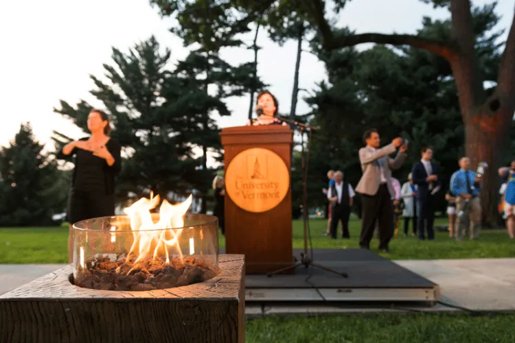 A flame burns in front of a podium that Provost Patricia Prelock stands behind.