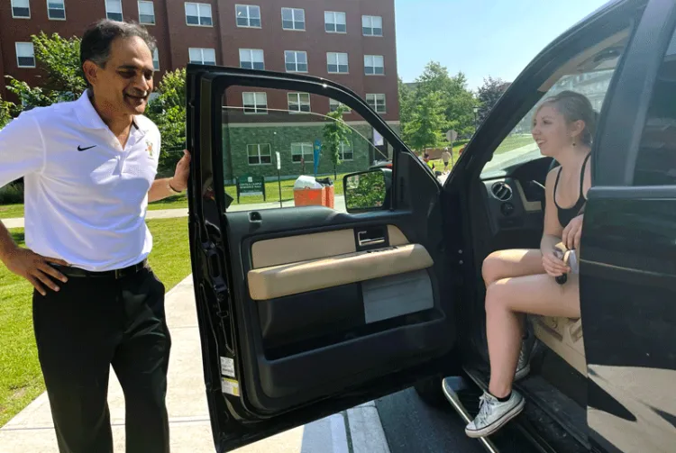 Suresh Garimella holds a car door open and talks to a student in the driver's seat