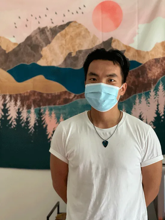 Jamie Dixon sands in front of tapestry in his dorm room.