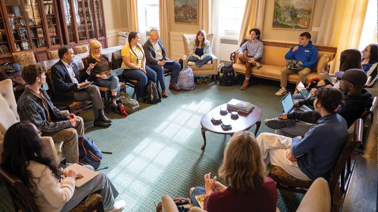 a group of people sits in chairs in a circle having a conversation