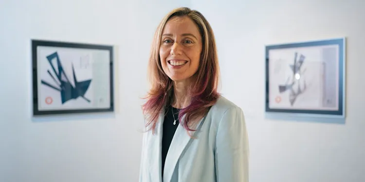 jen karson standing in in a white art gallery in front of two hung pieces