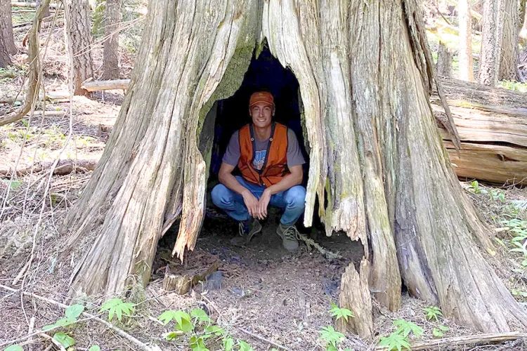 Jon Lewis sitting within a hollow tree stump