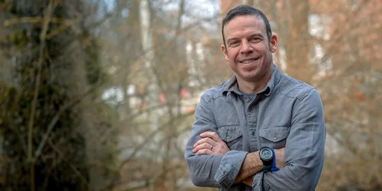 brendan fisher smiling in front of woods