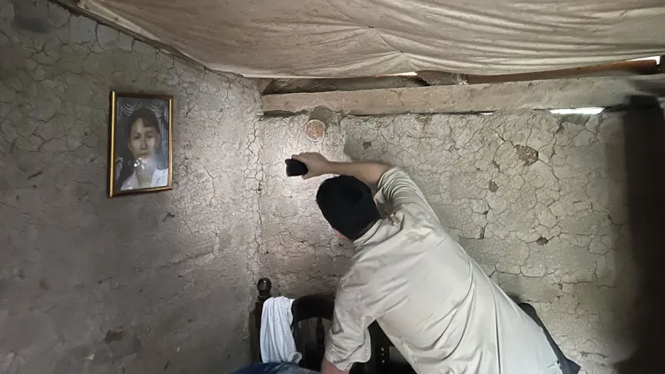 A person shining a flashlight toward a stone wall in a room with a fabric ceiling