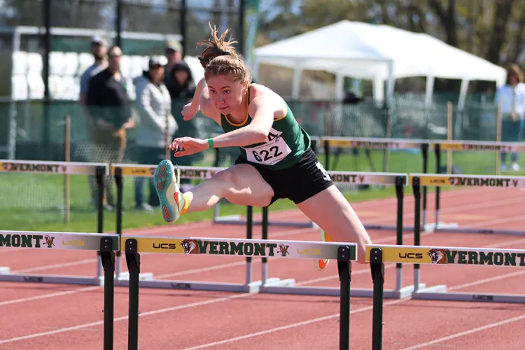 A student jumps over a hurdle on the track