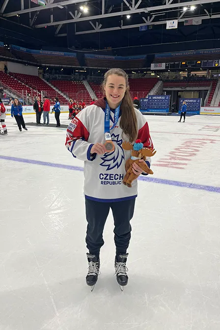 Tynka Pátková shows off her bronze medal while standing on an ice rink