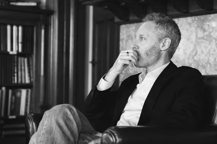 one professor holds his hand up to his mouth in thought