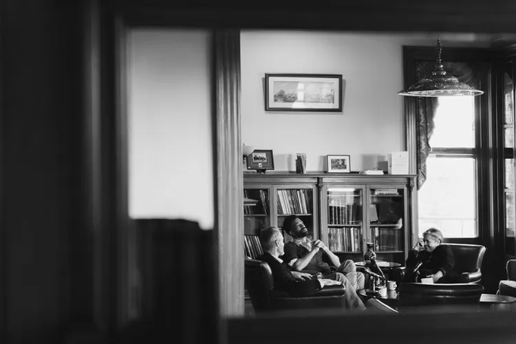 three professors sitting around a table reflected in a mirror