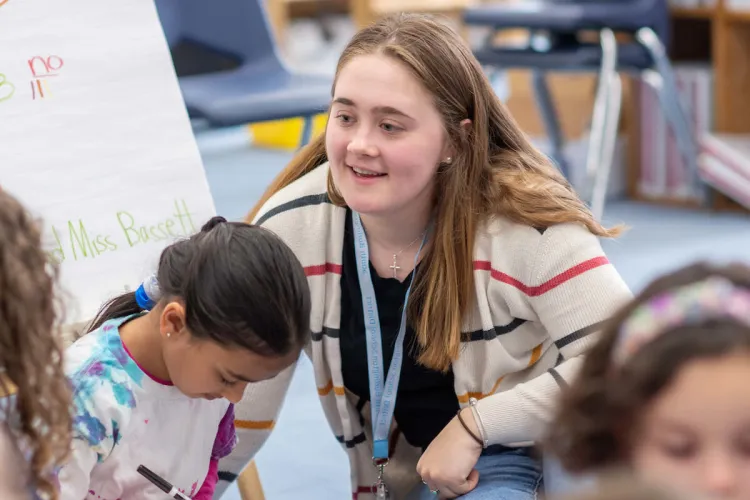 A student-teacher works with young children in the classroom