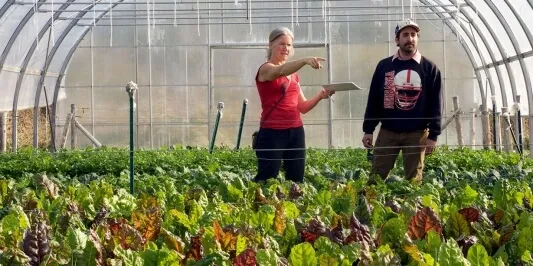 women pointing in a greenhouse