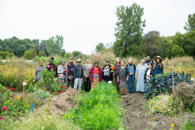 Students work with new farmers and stand together in a field
