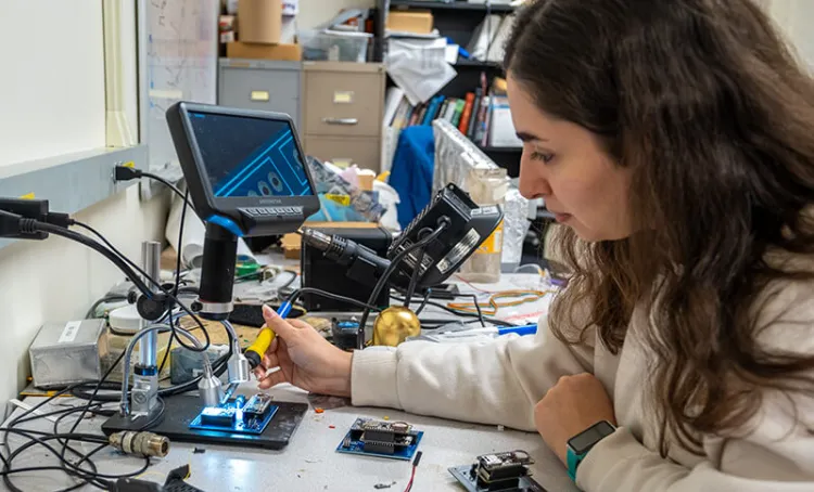 A graduate student builds a circuit board in an electrical engineering lab