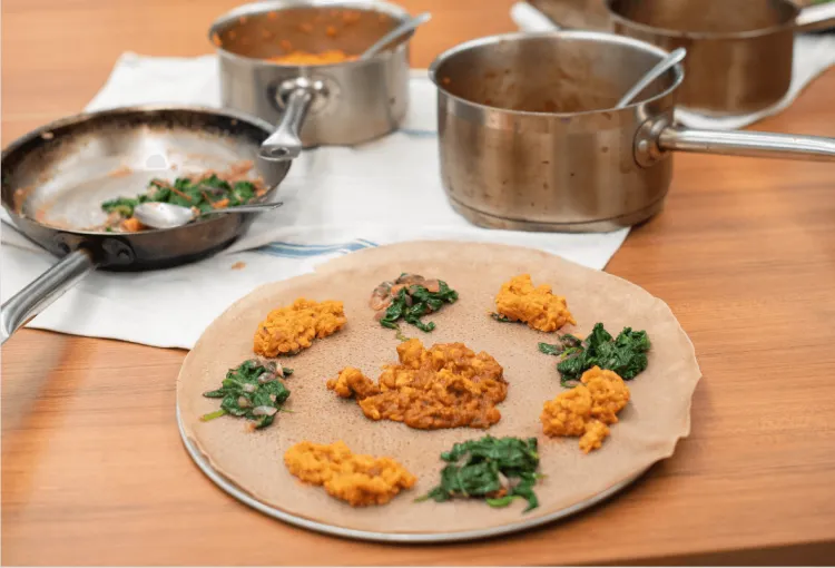 Servings of greens and lentils on injera