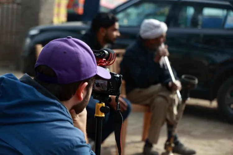 Picture of the back of a student wearing a purple ballcap is photographing two women.