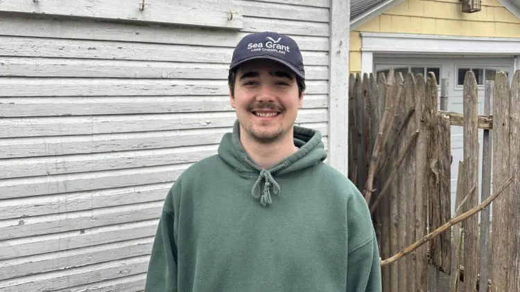 Gus standing outdoors in a Lake Champlain Sea Grant ball cap.
