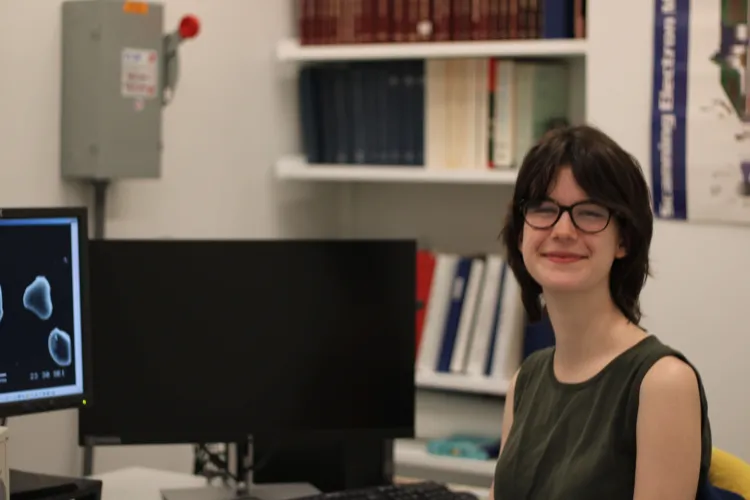 Student sitting by computer with research images on screen