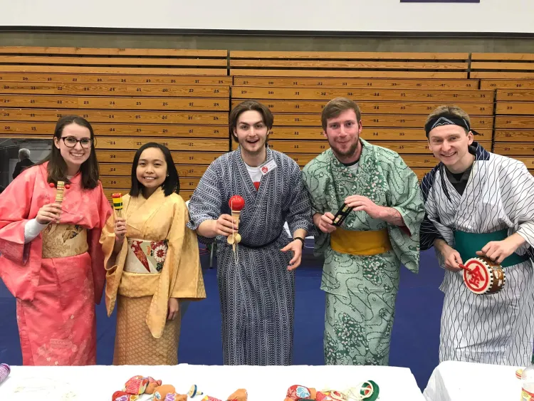 A group of individuals in Japanese dress, smiling and posing together for a photograph.