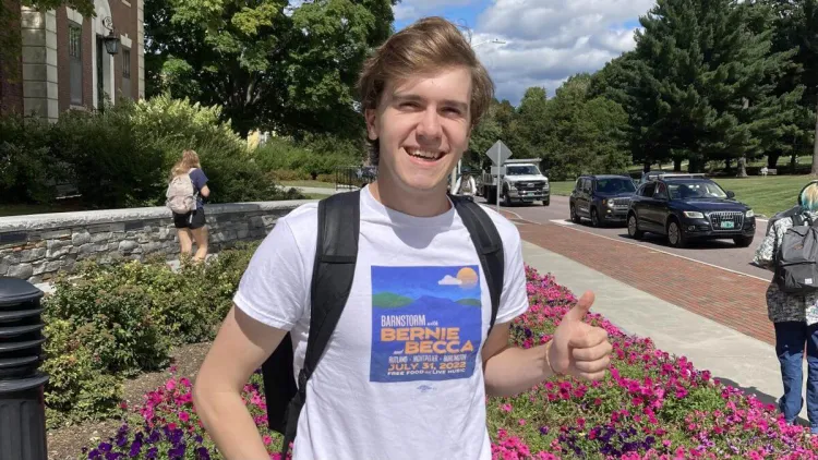 Chris standing outside of the Waterman Building on UVM's campus and giving a thumbs up