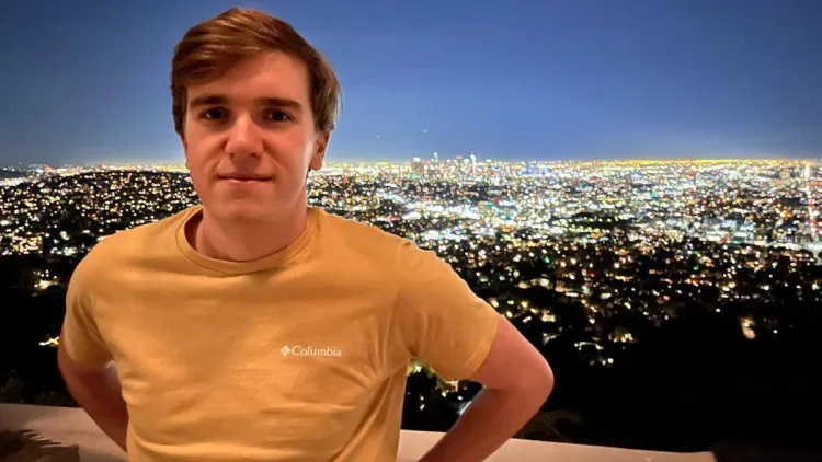 Chris posing in front of a bright nighttime city skyline.