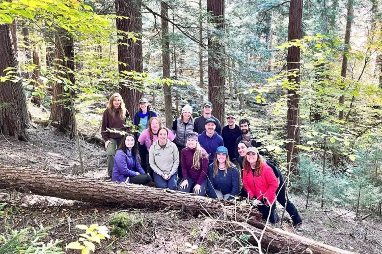 The group of students all together among standing and fallen trees in the forest