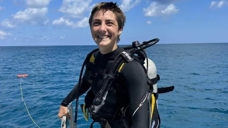 Emma in her scuba gear standing on a boat.