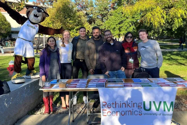 A group of students and the mascot Rally Cat at a club table outside on UVM's campus with a 