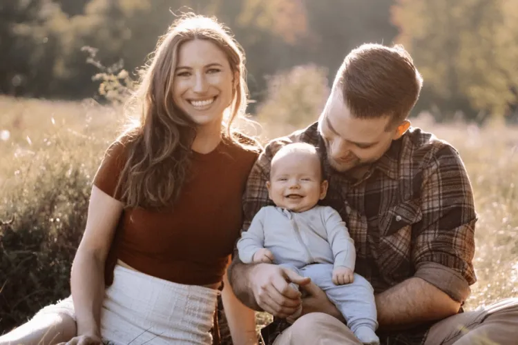 a woman, a man, and a baby smiling