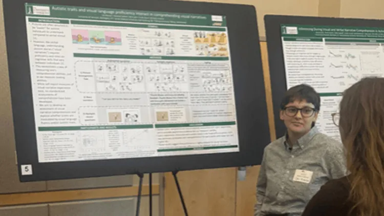 Del Rosner stands in front of a scientific poster engaged with another individual visiting the poster. 