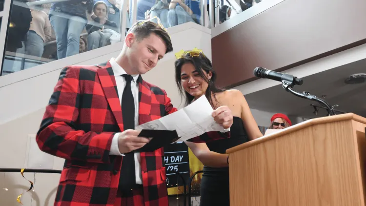 a man and a woman standing at a podium looking at a letter